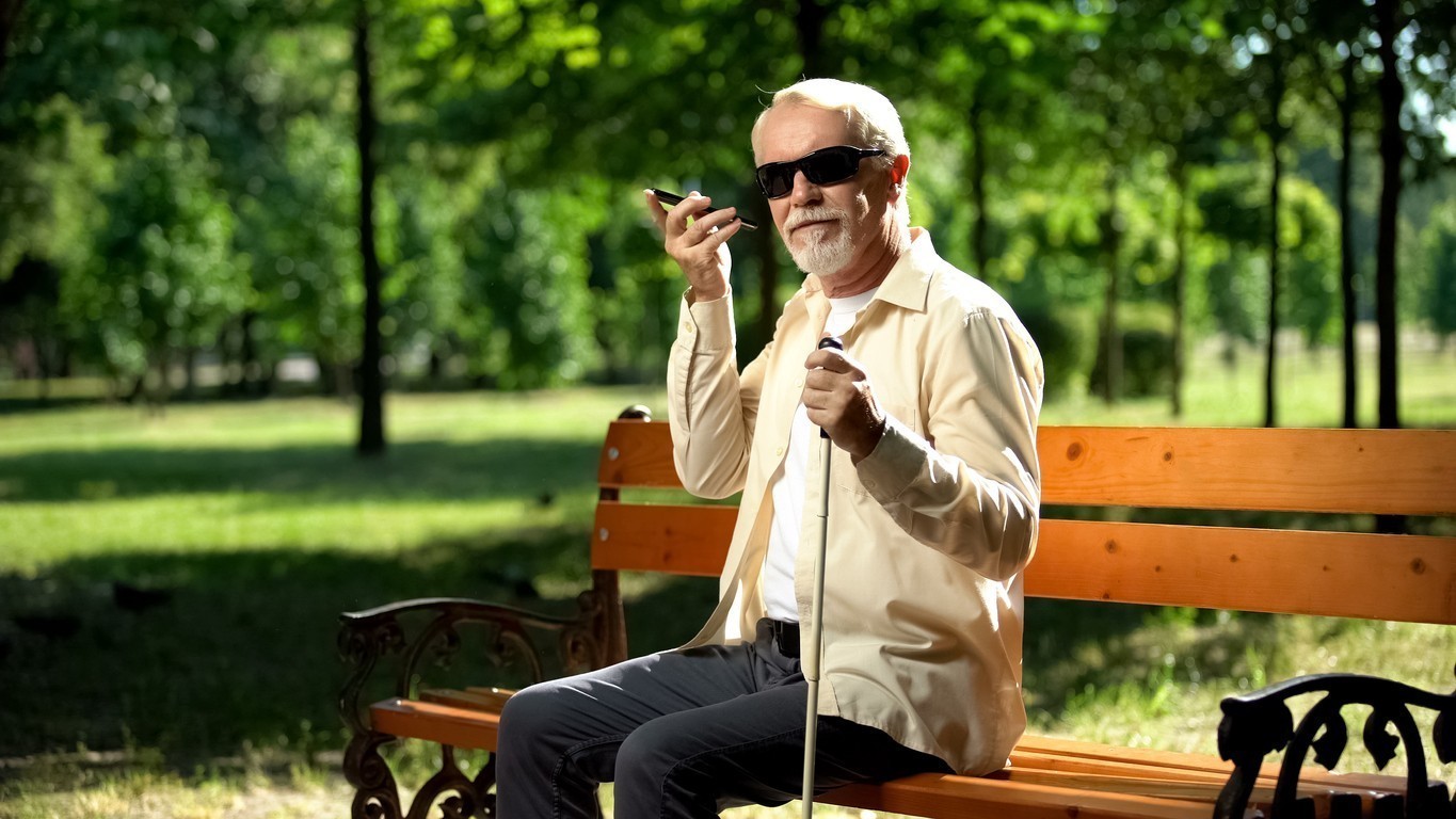 Visually impaired old man using voice control app in smartphone, innovations